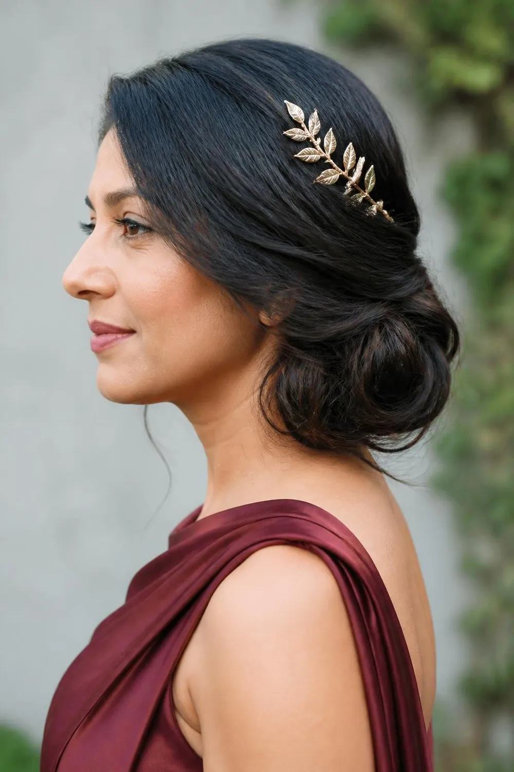 Low side chignon with a gold leaf hair comb on long hair
