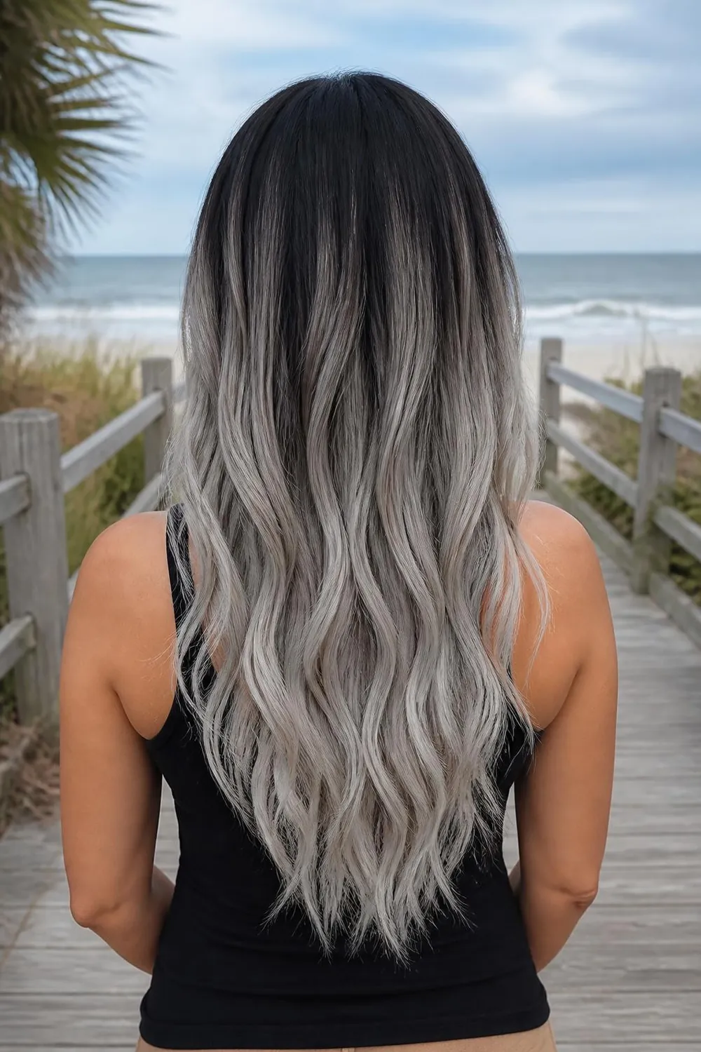 Dark brown roots fading into toned silver ends on long wavy hair