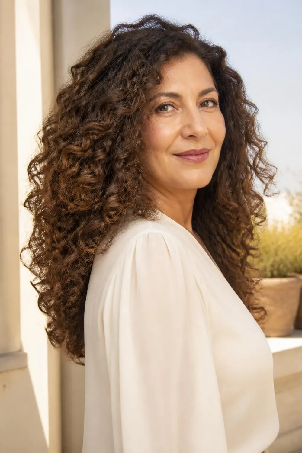 Long loose 3A curls with layers starting at the chin on a woman in her 50s