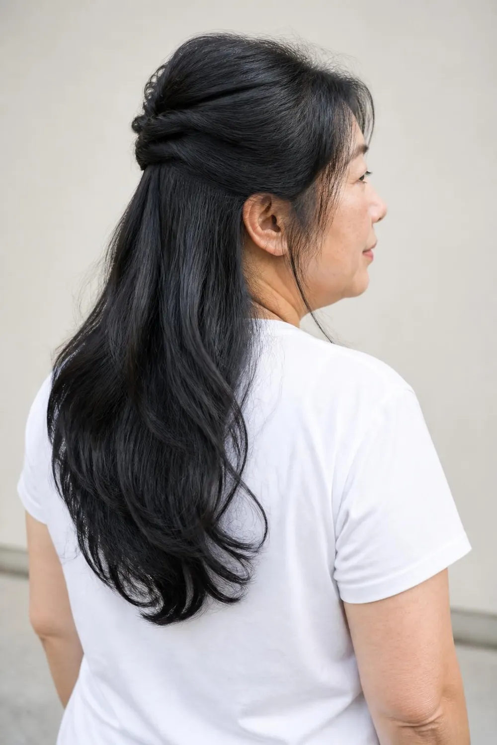Long layered hair worn half-up with a crown twist on a plus size woman over 50