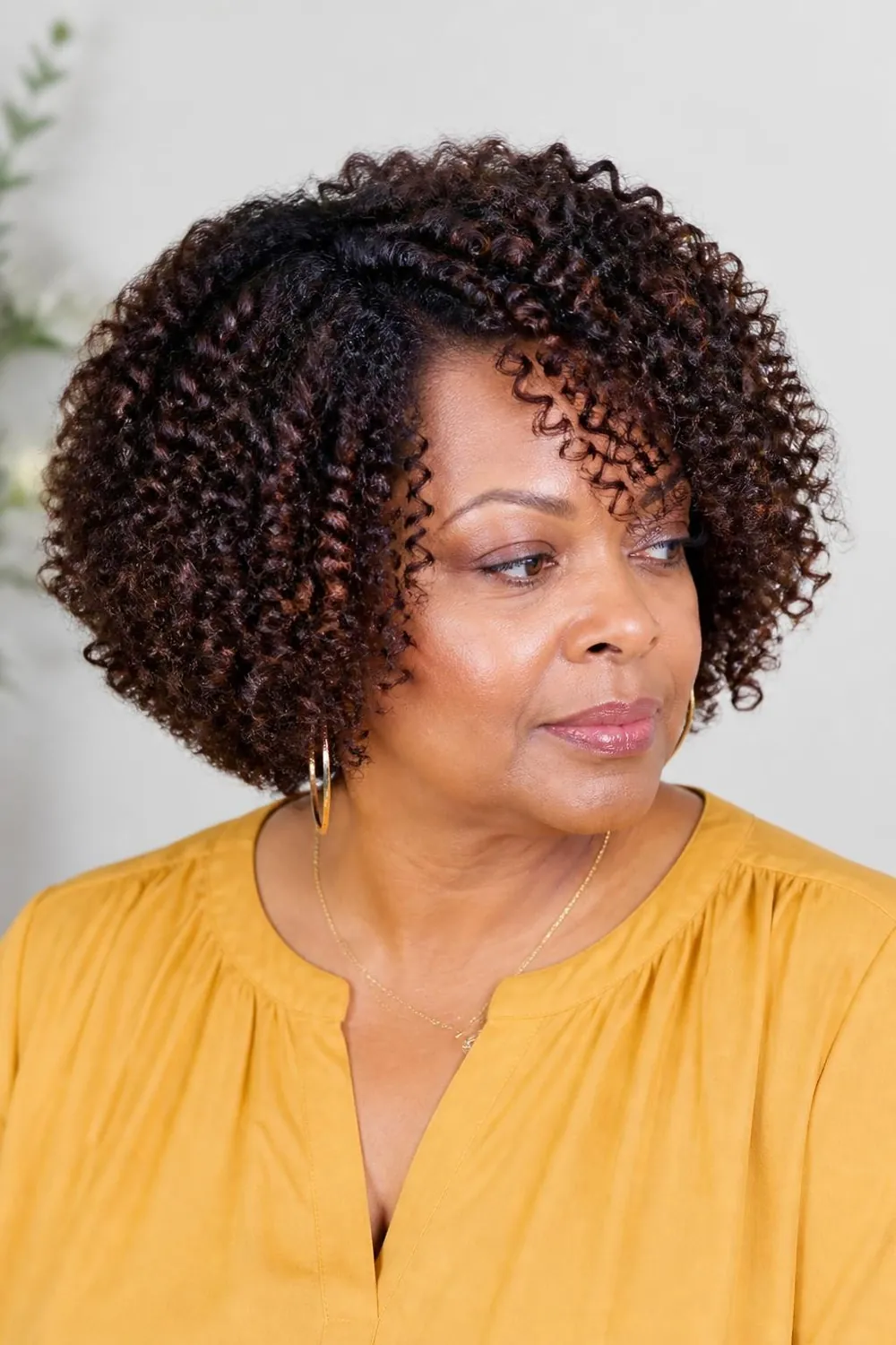 Angled curly bob longer in front for a round face over 50
