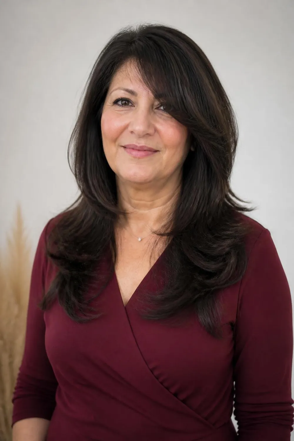 Long layered hair with long side-swept bangs for a woman over 50 with a round face