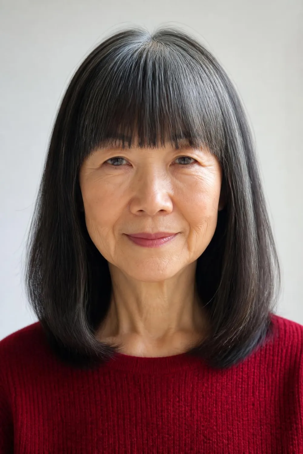 Shoulder-length cut with heavy blunt bangs for women over 60