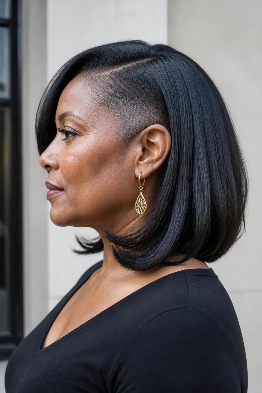 Collarbone haircut with a hidden side undercut above one ear on thick hair, woman over 50