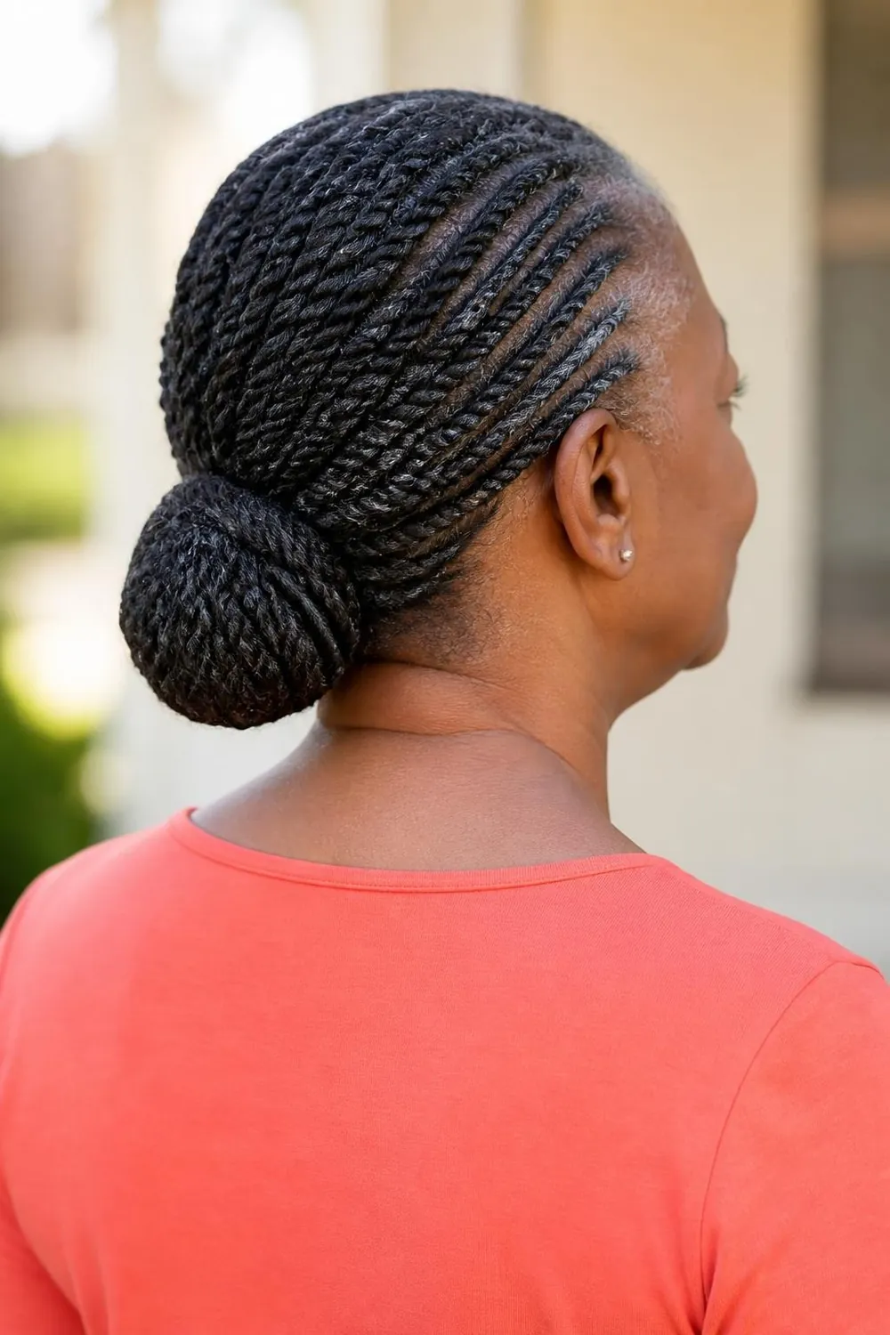Flat twists gathered into a low bun at the nape, back view, Black woman over 60
