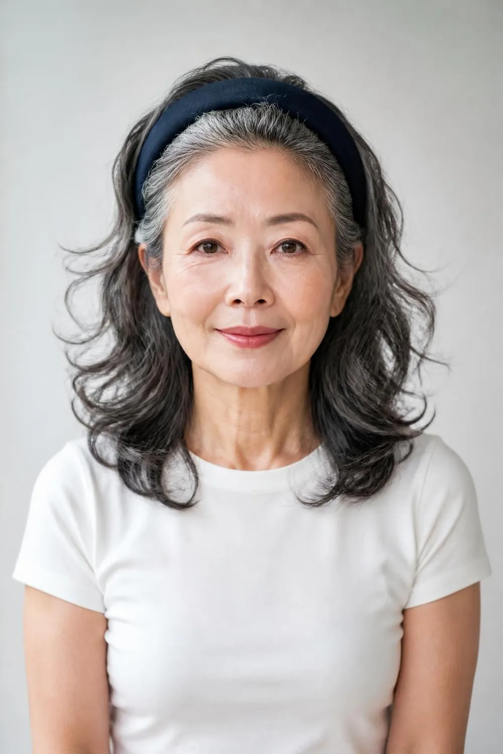 Medium wavy hair with a wide padded headband pushed back from the face, woman over 60