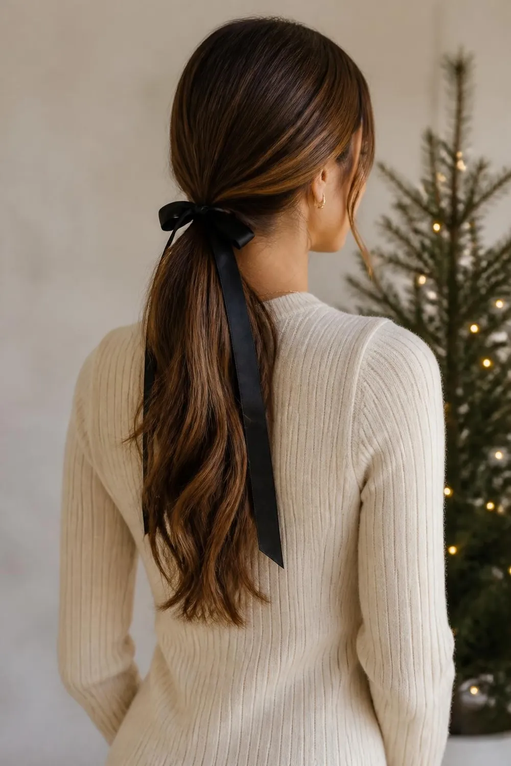 Low ponytail wrapped with a black satin ribbon tied in a bow
